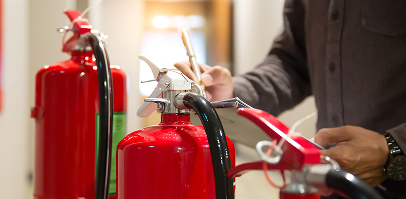 Person performing an inspection on fire extinguishers