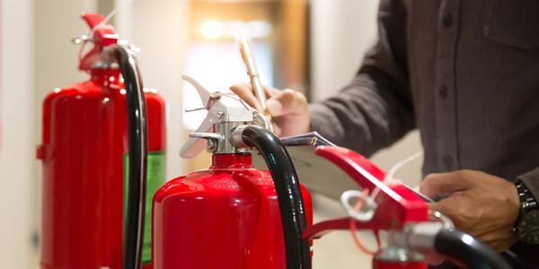 Person performing an inspection on fire extinguishers